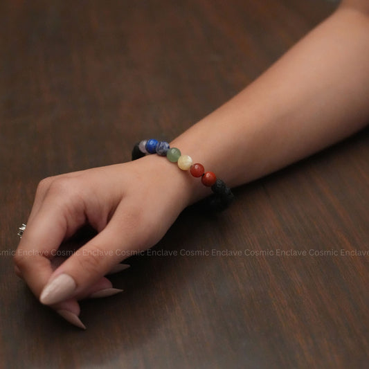 Close-up of a hand wearing a colorful 7 Chakra  beaded bracelet on a wooden surface