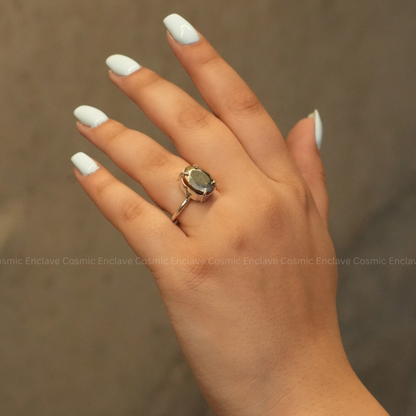 A hand showcasing a silver-colored ring with a precision-cut pyrite gemstone on the finger.