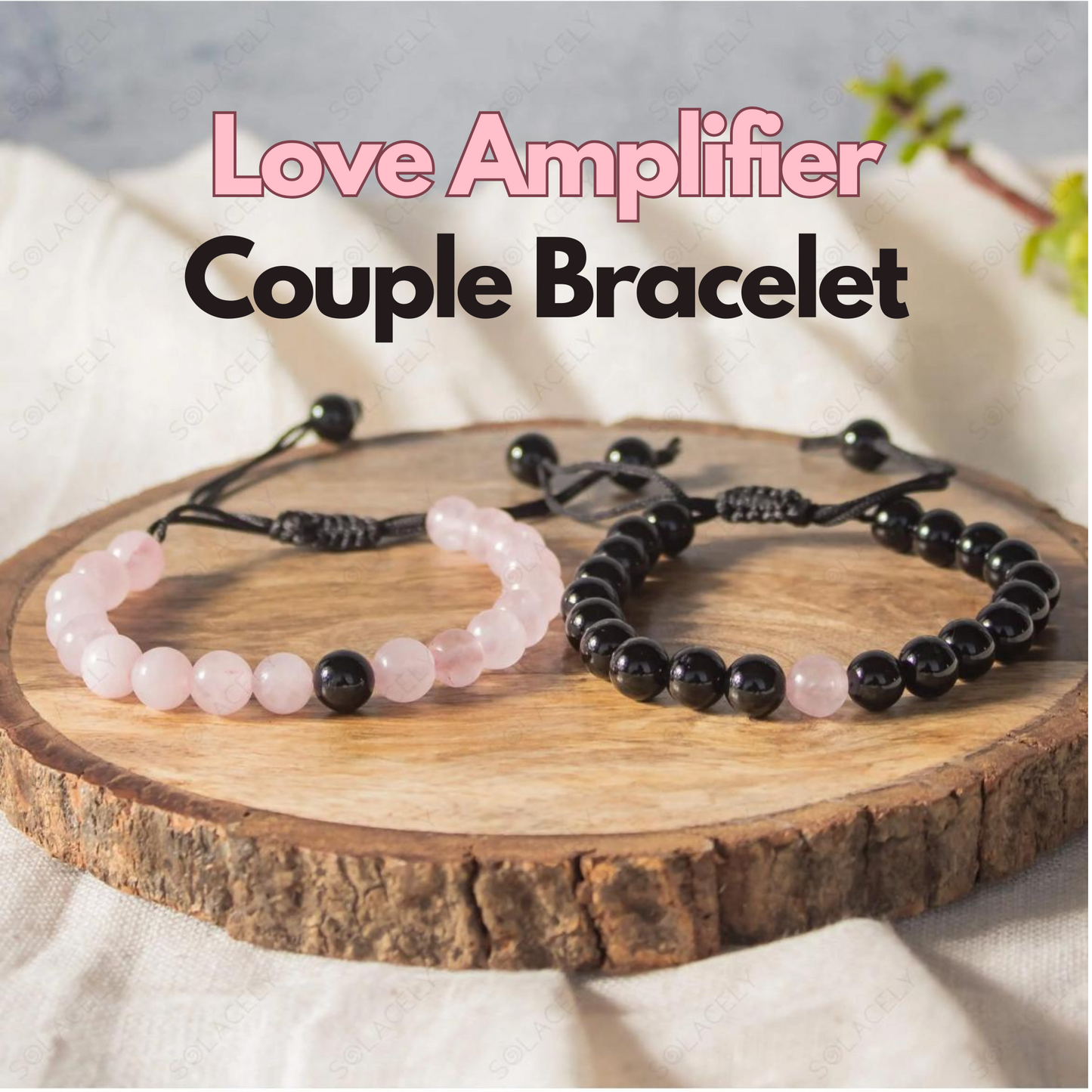 Two couple bracelets, one with pink rose quartz beads and the other with black tourmaline beads, displayed on a wooden stand with a title 'Love Amplifier Couple Bracelet'.