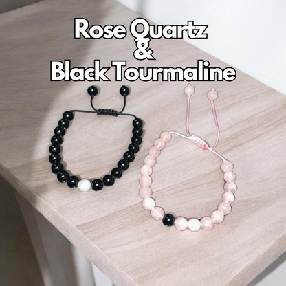 Two couple bracelets, one with pink rose quartz beads and the other with black tourmaline beads, Displayed on a wooden surface