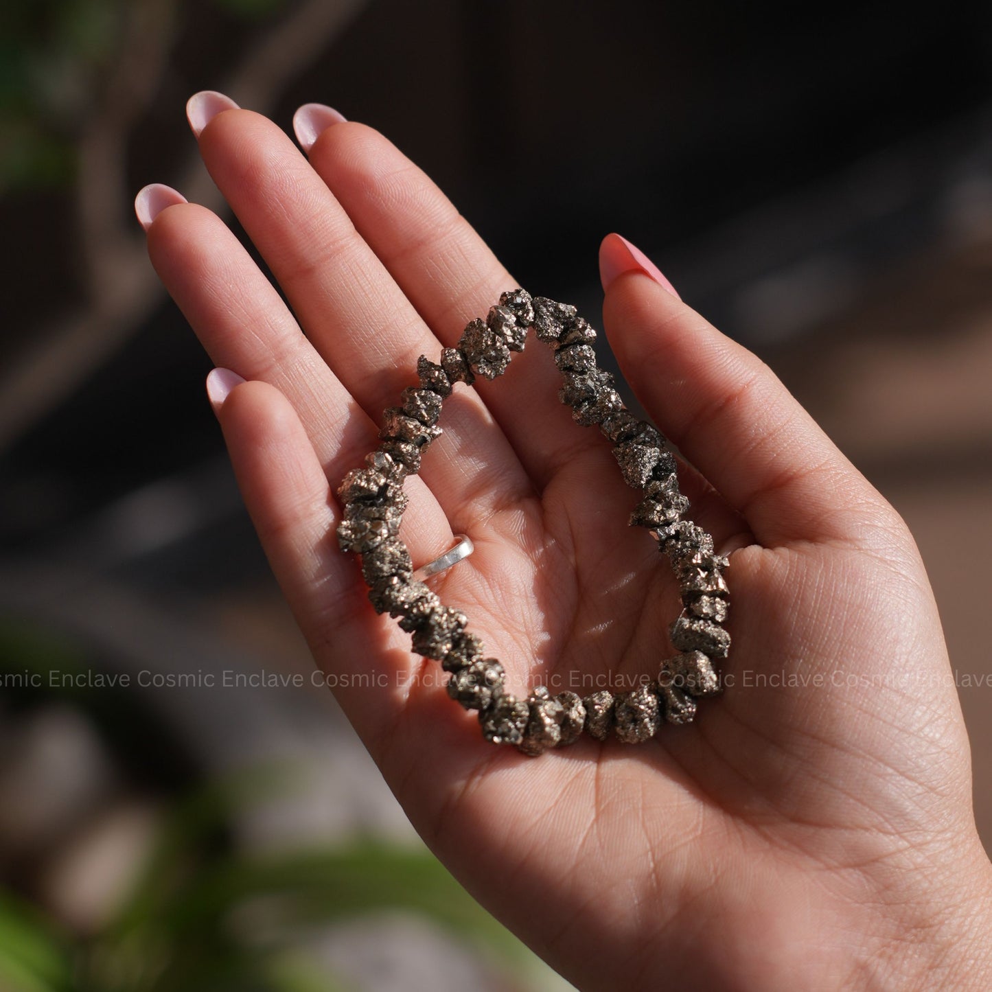 Hand holding a Pyrite Chips Bracelet with a blurred background