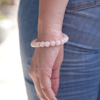 Person wearing a pink beaded Rose Quartz bracelet on a blurred background