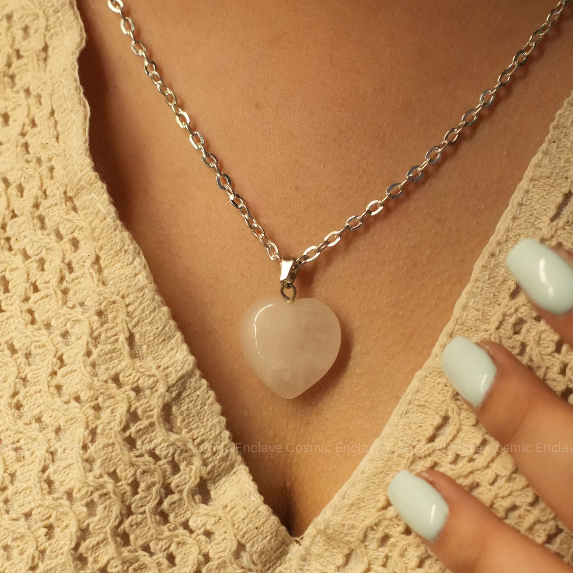 Necklace with a heart-shaped Rose Quartz pendant worn by a person in a beige lace garment.